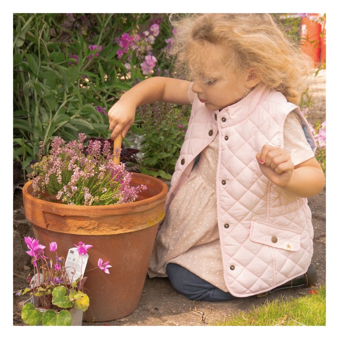 Child planting a flower in a pot with compost